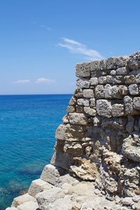 Stone wall by sea against sky