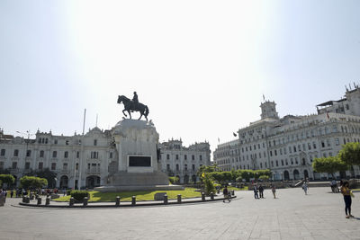 Statue in city against sky