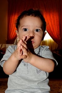 Portrait of cute boy clapping while kneeling at home