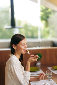 Smiling young woman drinking wine in restaurant