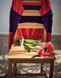 Pink tulip on wooden chair with colorful cardigan draped over the back of chair, vintage style