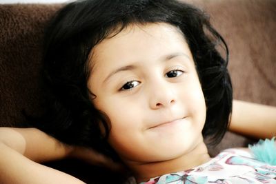 Close-up portrait of cute baby girl relaxing on bed at home