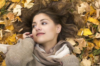 Portrait of young woman lying on dry leaves