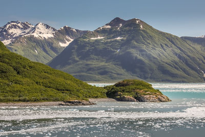 Scenic view of sea by mountains against sky