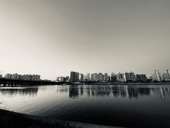 Buildings by river against sky in city