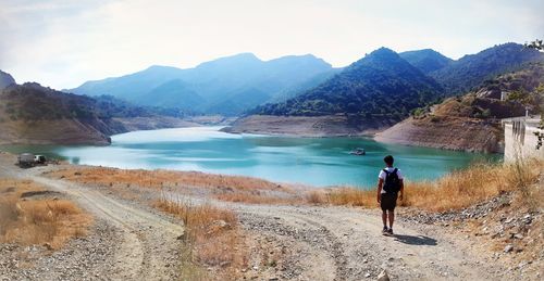 Rear view of man on lake against mountains