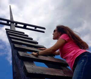 Low angle view of young woman climbing on ladder