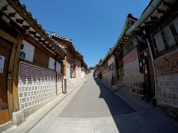 Walkway amidst buildings against clear sky