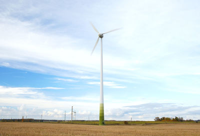 Low angle view of windmills on landscape against sky