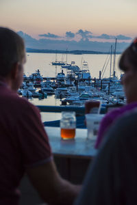 Rear view of man sitting in sea against sky