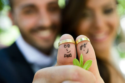 Anthropomorphic faces drawn on thumbs with rings of wedding couple