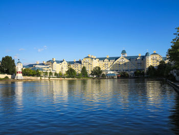 Buildings at waterfront against blue sky