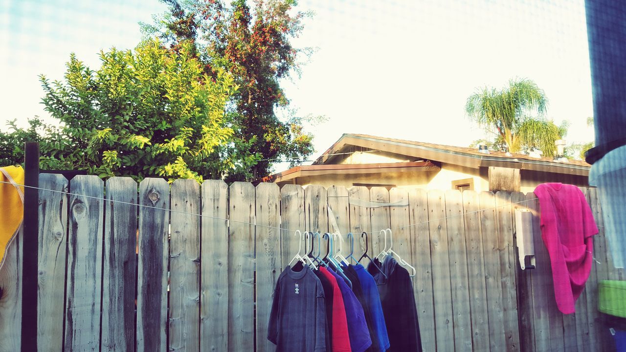 wood - material, wooden, tree, built structure, building exterior, wood, house, day, architecture, outdoors, clothing, fence, blue, no people, bench, in a row, multi colored, drying, relaxation, sunlight