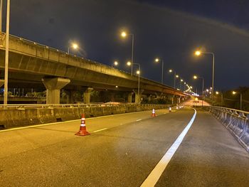 Illuminated bridge over road in city at night