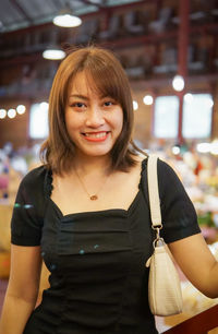 Portrait of young woman standing against store