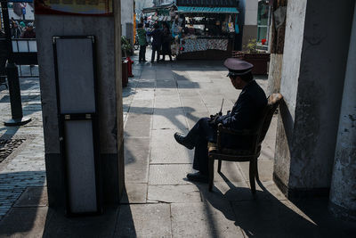 Security guard sitting on chair against building wall