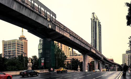 Bridge over city street and buildings against clear sky