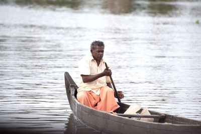 Side view of a man sitting on boat in lake