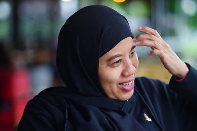 Portrait of indonesian muslim woman wearing black hijab with bokeh.