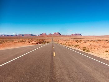 Road passing through desert against blue sky in arizona 