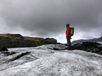 Man standing on rock against sky