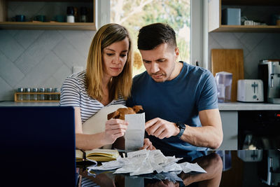 Man and woman checking payment bills in the kitchen at home. planning family budget