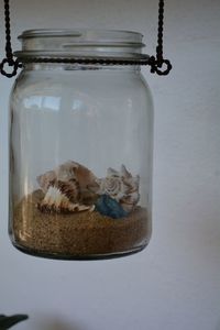 Close-up of sand and seashells in a glass jar.