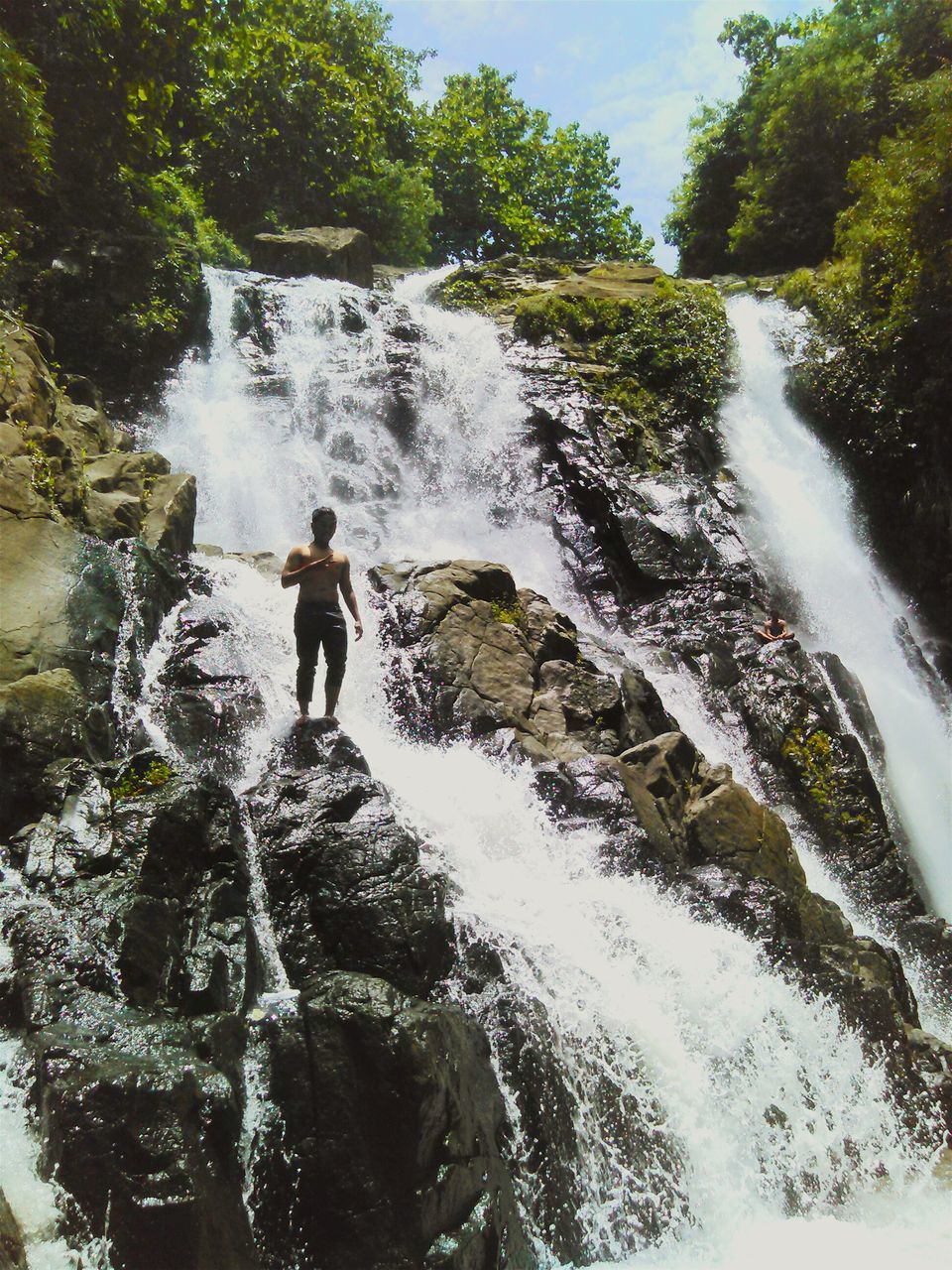 water, motion, lifestyles, leisure activity, full length, men, waterfall, splashing, flowing water, rear view, long exposure, nature, surf, standing, rock - object, tree, walking, beauty in nature