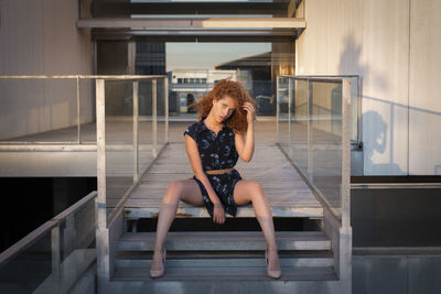 Portrait of a curly-haired woman at sunset sitting on some stairs