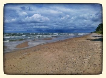 Scenic view of beach against cloudy sky