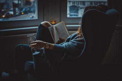 Side view of young woman reading book