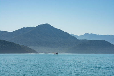 Scenic view of sea and mountains against clear sky