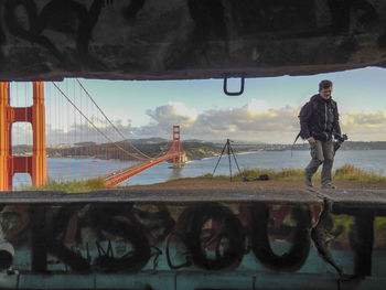 Man standing by bridge against sky