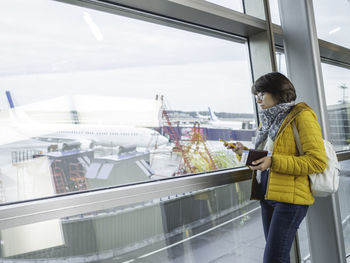 Woman with passport and boarding pass near window at airport.tourist registers online in application