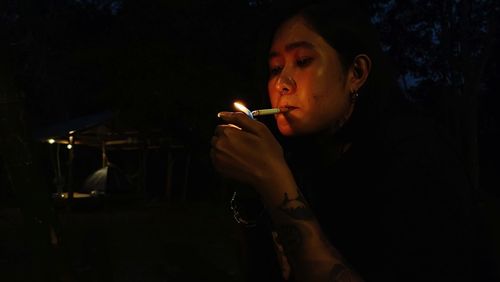 Young woman smoking cigarette at night