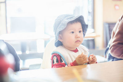 Portrait of cute boy sitting on table at home