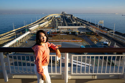 Portrait of woman standing by railing against sea