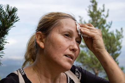 Close-up of tired woman wiping sweat