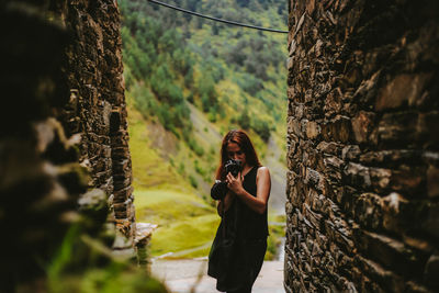 Woman photographing in alley between walls