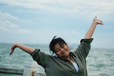 Portrait of smiling young woman in sea against sky