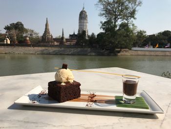 Cake with hot chocolate in tray on table at lakeshore