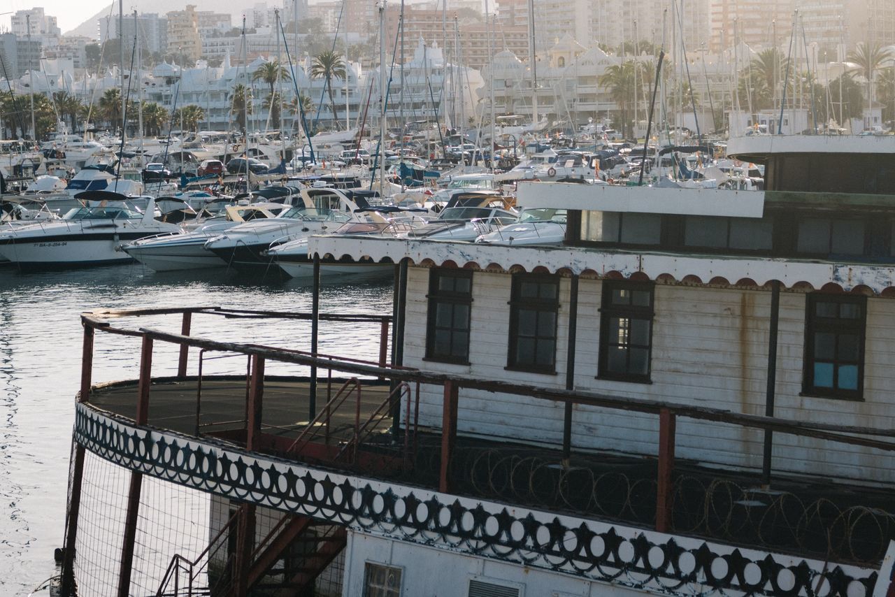 BOATS MOORED IN HARBOR AT CITY