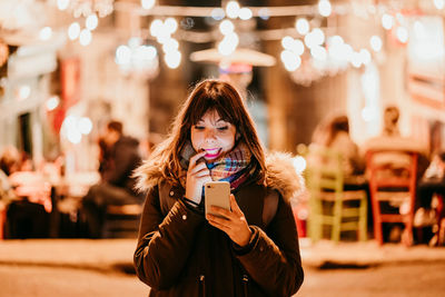 Portrait of smiling young woman using mobile phone