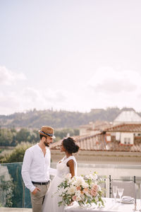 Couple holding flower against sky