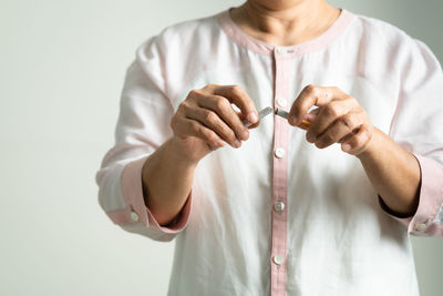 Midsection of woman holding hands over white background