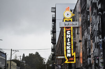 Low angle view of information sign on road against buildings in city