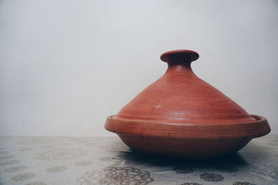 Close-up of vase on table against wall