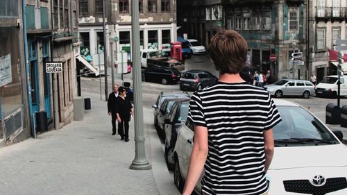 Rear view of man walking on footpath in city