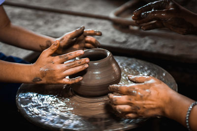 Cropped hands of people making pot in workshop