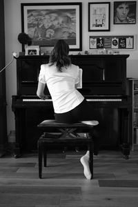 Rear view of girl playing piano at home